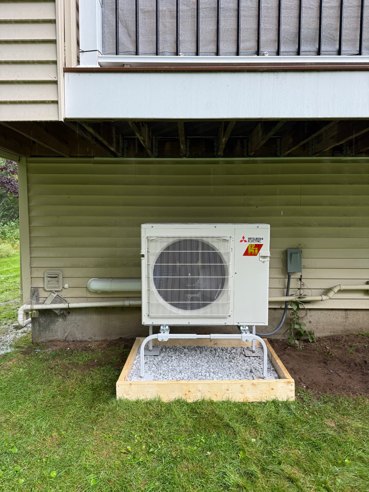 Mitsubishi hyper-heat condenser set on a gravel pad beside a home