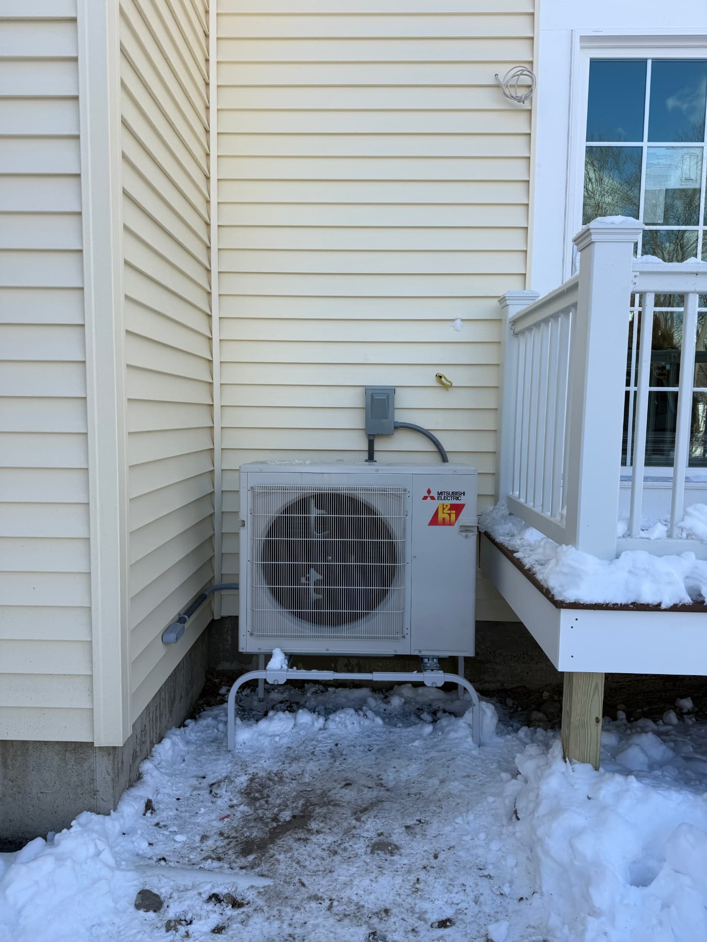 Mitsubishi hyper-heat condenser on a snow stand beside a deck